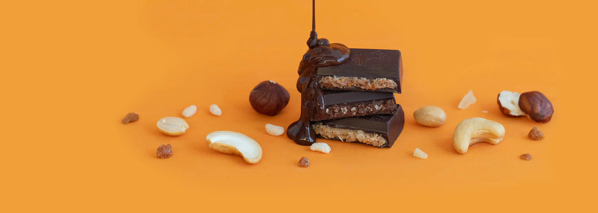 Chocolate-covered bars with nuts on an orange background
