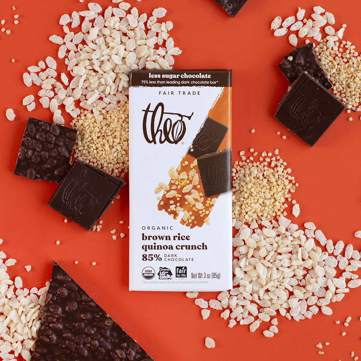 Bar of 85% dark chocolate with brown rice quinoa crunch on a red background with rice crisps and quinoa.